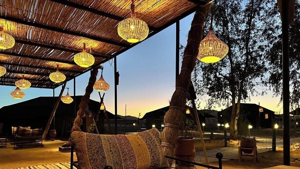 An outdoor seating area with woven light fixtures, a patterned sofa, and a rustic ambiance. - Beautiful 1-bedroom campground in Merzouga for a peaceful escape (Merzouga)