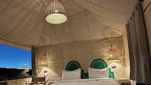 A tented room with a bed, two chairs, and two hanging lamps. - Beautiful 1-bedroom campground in Merzouga for a peaceful escape (Merzouga)