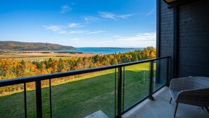 A balcony with a view of a lake, trees, and distant hills.