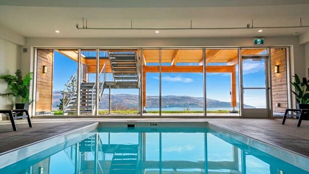 A swimming pool with a view of a mountainous landscape through large glass doors.