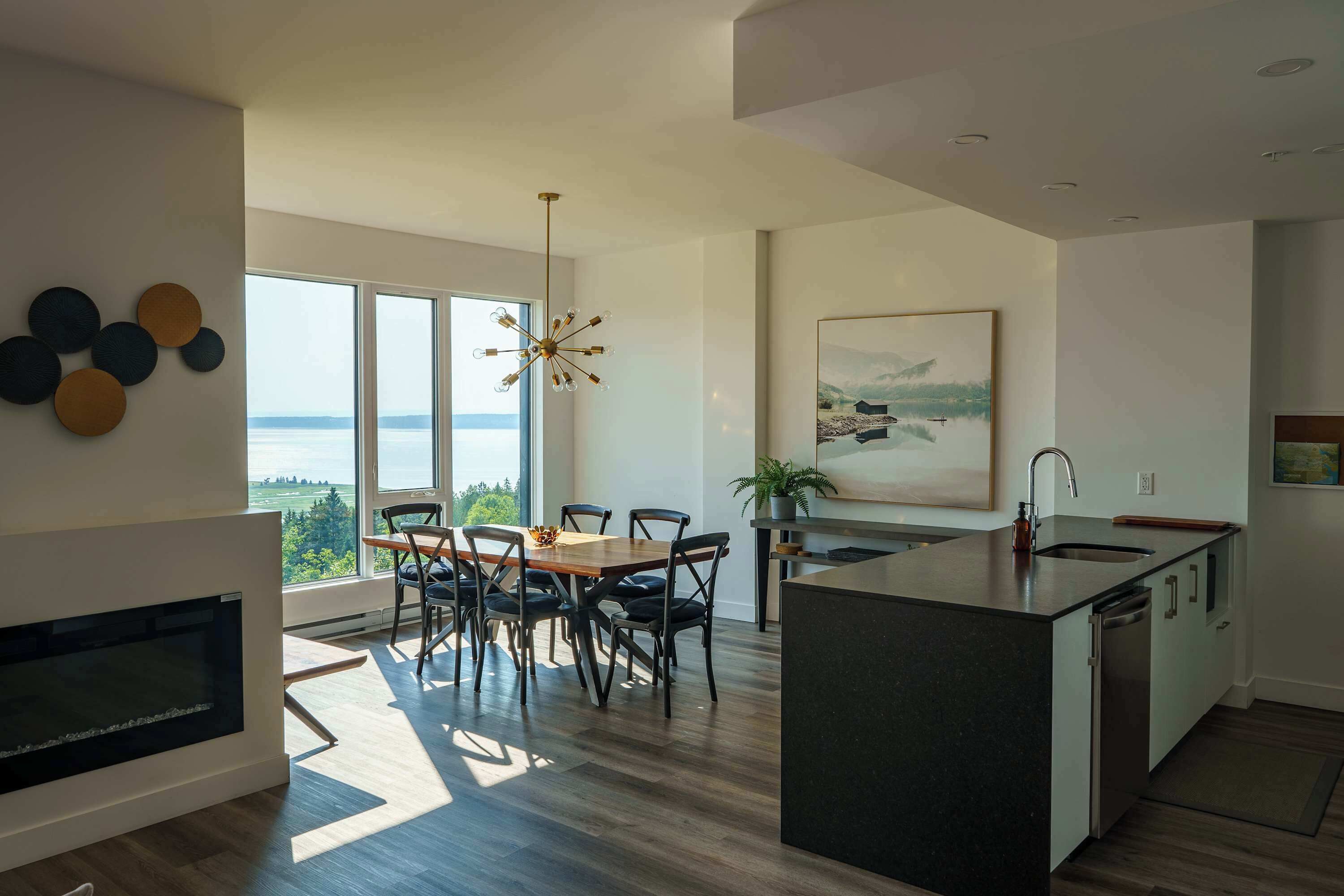 A modern kitchen with a large island, dining area with chairs, and a view of the outdoors.