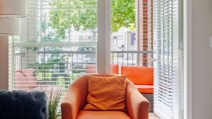 A modern living room with a black sofa, an orange armchair, and a floor lamp. - Tangerine 2Bed 2Bath at 5 min walk to NRG near TMC (Houston)