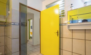 Une salle de bain avec une porte jaune, un miroir et un sol carrelé.