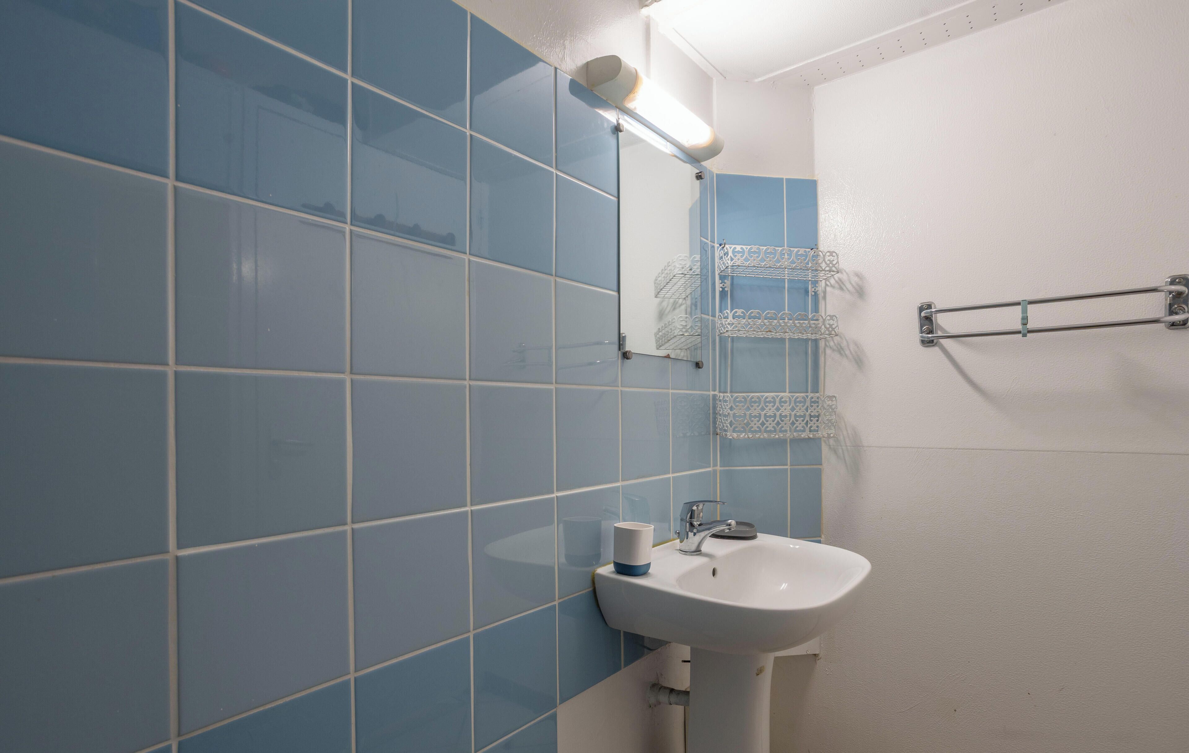 Une salle de bain avec des carreaux bleus, un lavabo blanc et un porte-serviettes.