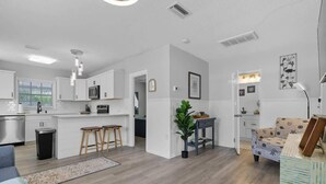 Una cocina moderna con armarios blancos, una isla central y taburetes de madera.