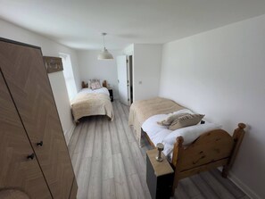 A bedroom with two beds, a wardrobe, and a hanging light fixture. - Light House (Sleeps 9) (Swindon)
