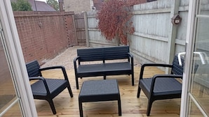 Une terrasse avec une plateforme en bois, un banc noir et une petite table.
