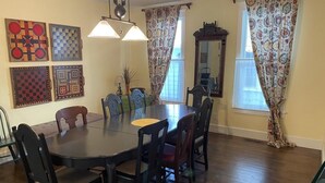 Comedor con una mesa redonda y sillas, cortinas estampadas y decoración en la pared.