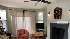Una sala de estar con sofá, sillón, mesa de centro, chimenea, televisor y estanterías decorativas.