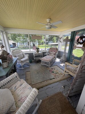 A covered porch with wicker furniture, a ceiling fan, and a view of the backyard. - Cottage Close to the Lake! (Lakeside)