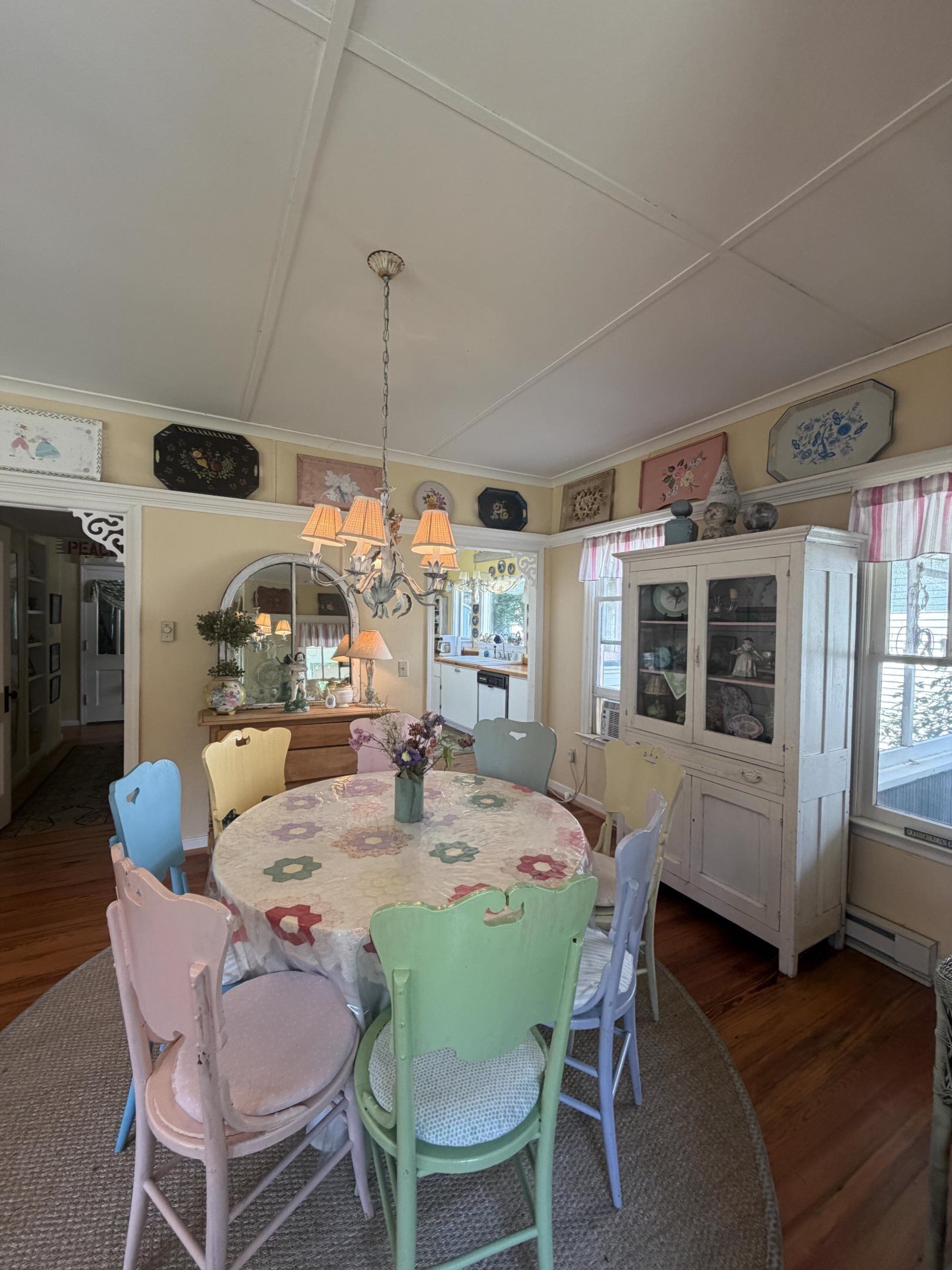 A dining room with a round table, chairs, a chandelier, and a cabinet with glass doors.