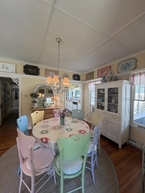 A dining room with a round table, chairs, a chandelier, and a cabinet with glass doors. - Cottage Close to the Lake! (Lakeside)