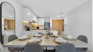 Un comedor moderno con una mesa de mármol, sillas grises y una cocina al fondo.