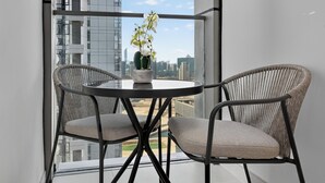 A balcony with two wicker chairs, a small round table, and a potted plant. - Radiant Boulevard by DVH Luxe Retreats (Abu Dhabi)
