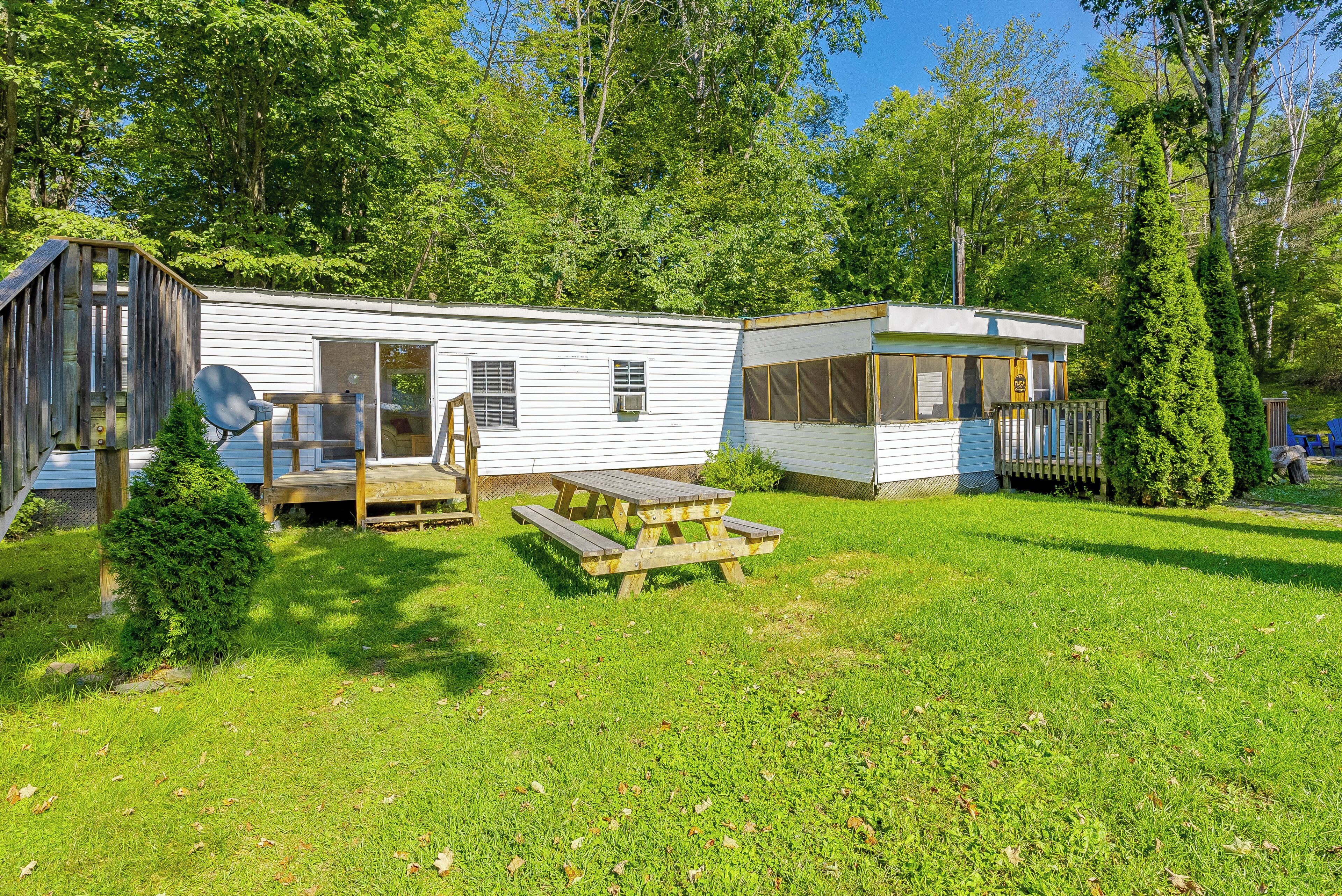 A mobile home with a deck and a small attached structure, both with windows and a door.