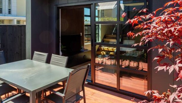Una casa moderna con un patio, una mesa de comedor y sillas.