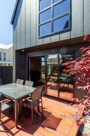 A modern house with a patio, a dining table, and chairs. - Urban Loft Near Westfield Mall | Walk Everywhere (Christchurch)