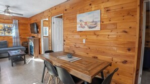 Une pièce aux murs lambrés, comprenant une table à manger, des chaises, un canapé et un téléviseur.