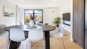 Un espace de salle à manger moderne avec une table ronde, des chaises blanches et un vase rempli de fleurs.