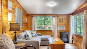 A cozy cabin interior with a sofa, a table, and a fireplace. - Springwood Cottage Resort - Cottage 5 (Arden)