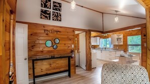 A wooden interior with a dining area, kitchen, and a wall with 'ENJOY' written on it. - Springwood Cottage Resort - Cottage 5 (Arden)