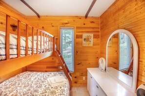 A wooden cabin room with a bunk bed, a small window, a dresser, and a mirror. - Springwood Cottage Resort - Cottage 6 (Arden)