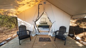 A tent with two black chairs and a bed inside.