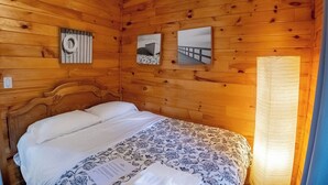 Een kamer met houten lambrisering, een bed, een reddingsboei aan de muur en twee ingelijste foto's.