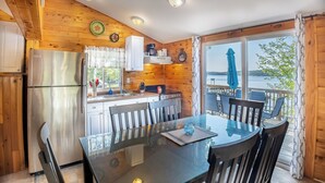 Eine Holzhütte mit Küche, Essbereich und einem Balkon mit Seeblick.