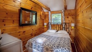 Ein Schlafzimmer einer Holzhütte mit einem Bett, einem Spiegel und einem Fenster.