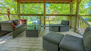 A covered outdoor seating area with wicker furniture and a glass coffee table. - Springwood Cottage Resort - Cottage 12 (Arden)