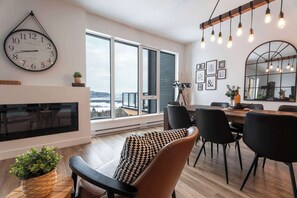 Un salon moderne avec une grande horloge murale, un coin repas avec des chaises et de grandes fenĂȘtres.