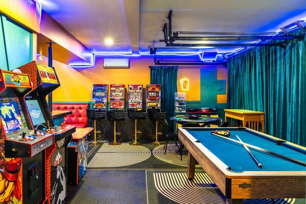 A pool table, arcade machines, and a billiards table in a room with teal curtains and a neon sign. - Playhaus Poconos - Sauna, Hottub, Arcade, Karaoke (Tobyhanna)