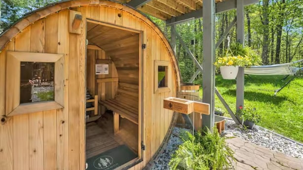 Une cabane en bois à l’extérieur incurvé, avec un petit porche et un hamac.