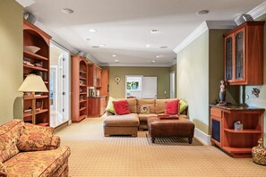 Ein Wohnzimmer mit Sofa, Hocker und Bücherregal.