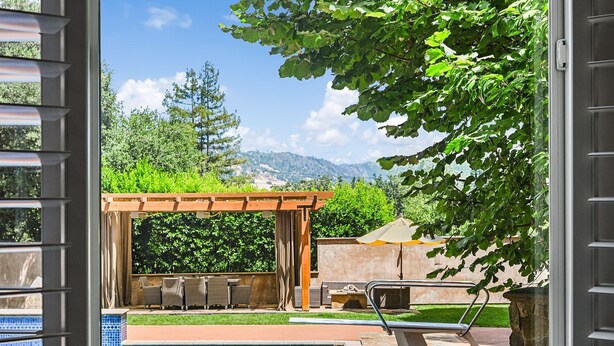 A pool with a pergola and chairs, a stone wall, and a view of mountains. - The Hideaway | Pool,Tennis Court, Outdoor Kitchen (Santa Rosa)