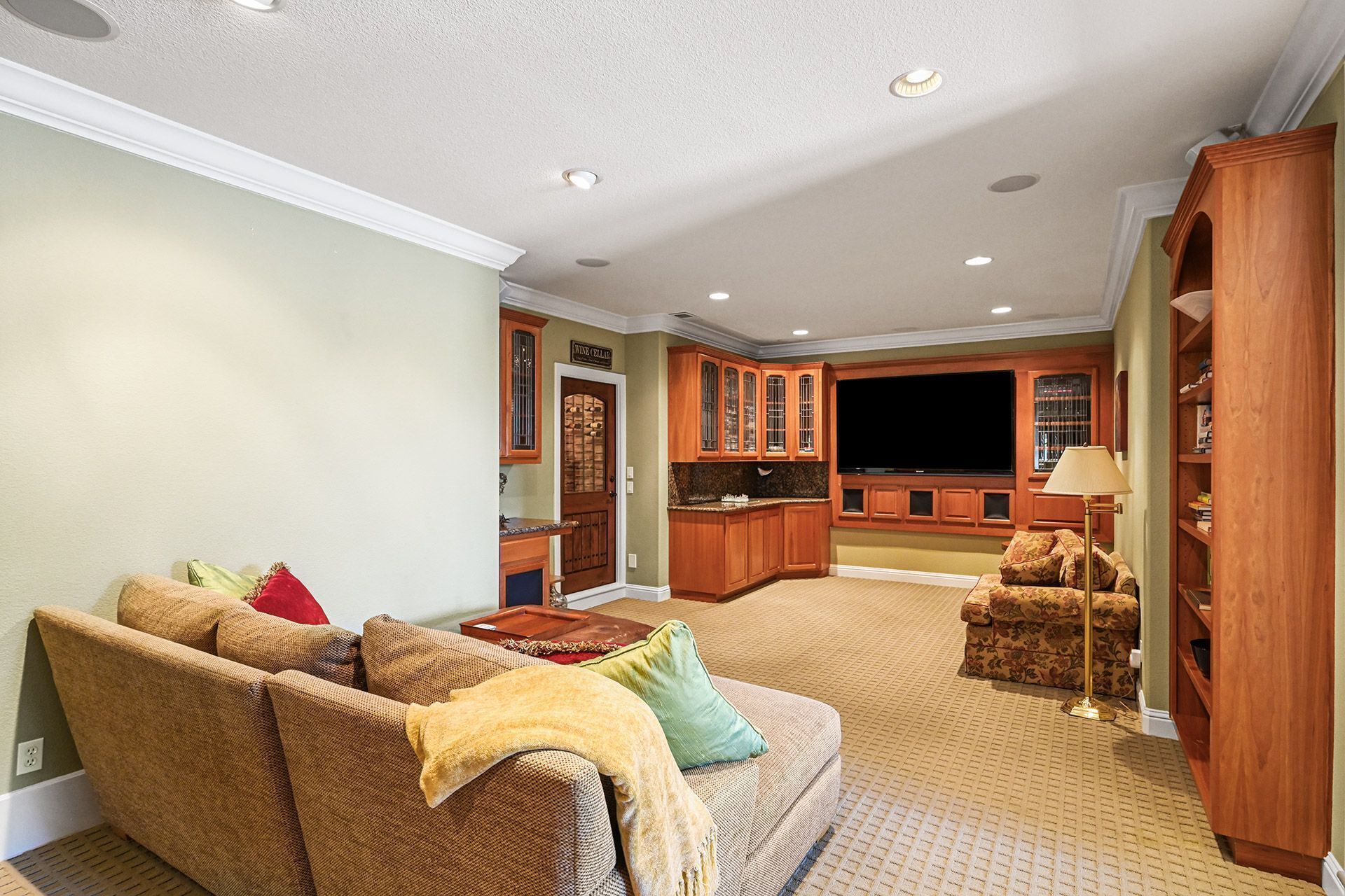 A living room with a sofa, a TV, wooden cabinets, and a carpeted floor.