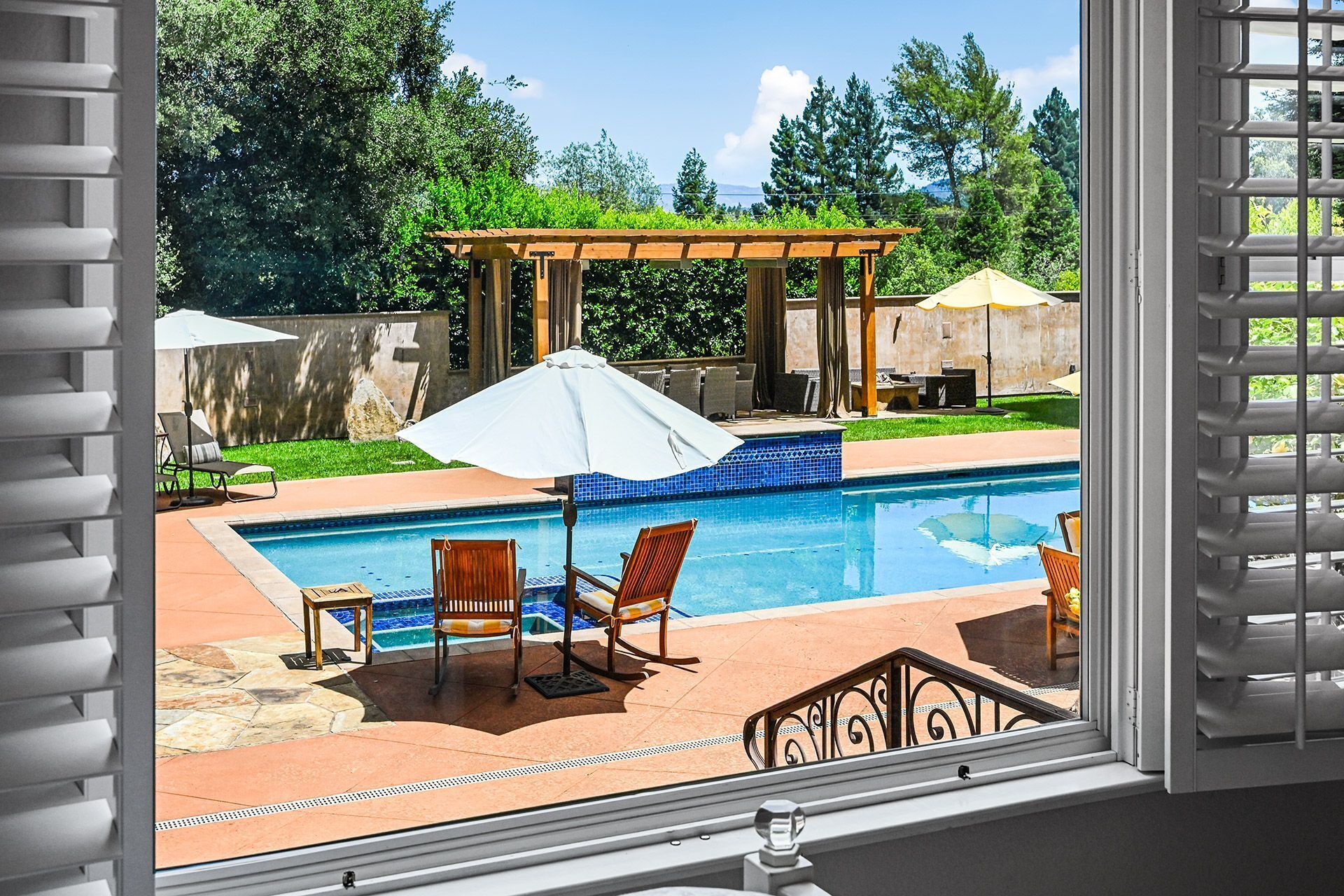 A pool with lounge chairs and a pergola.