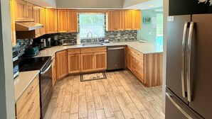 Una cocina moderna con armarios de madera, un refrigerador de acero inoxidable y un ventilador de techo.