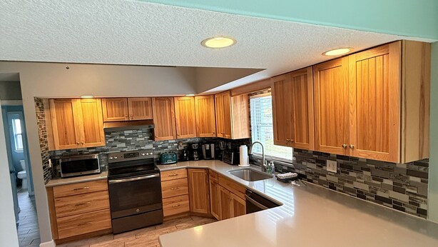 Una cocina moderna con armarios de madera, una isla grande y un protector contra salpicaduras de piedra.