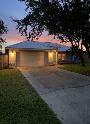 A residential garage with a metal roof, a concrete driveway, and a well-maintained lawn.