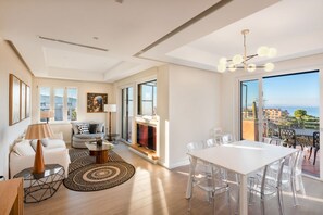 A spacious living room with a fireplace, a dining area with clear chairs, and a balcony with a view of the sea. - Lux 4BR Sorrento Home with SeaView Terrace (Sorrento)
