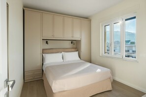 A bedroom with a bed, a wardrobe, a window, and a view of buildings. - Lux 4BR Sorrento Home with SeaView Terrace (Sorrento)