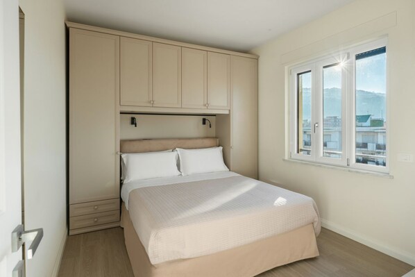 A bedroom with a bed, a wardrobe, a window, and a view of buildings. - Lux 4BR Sorrento Home with SeaView Terrace (Sorrento)