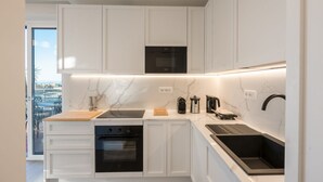 A modern kitchen with white cabinetry, a built-in oven, a coffee machine, and a black countertop sink. - Lux 4BR Sorrento Home with SeaView Terrace (Sorrento)