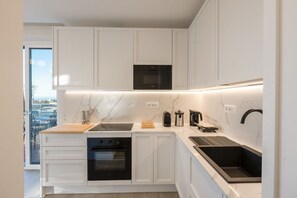 A modern kitchen with white cabinetry, a built-in oven, a coffee machine, and a black countertop sink. - Lux 4BR Sorrento Home with SeaView Terrace (Sorrento)