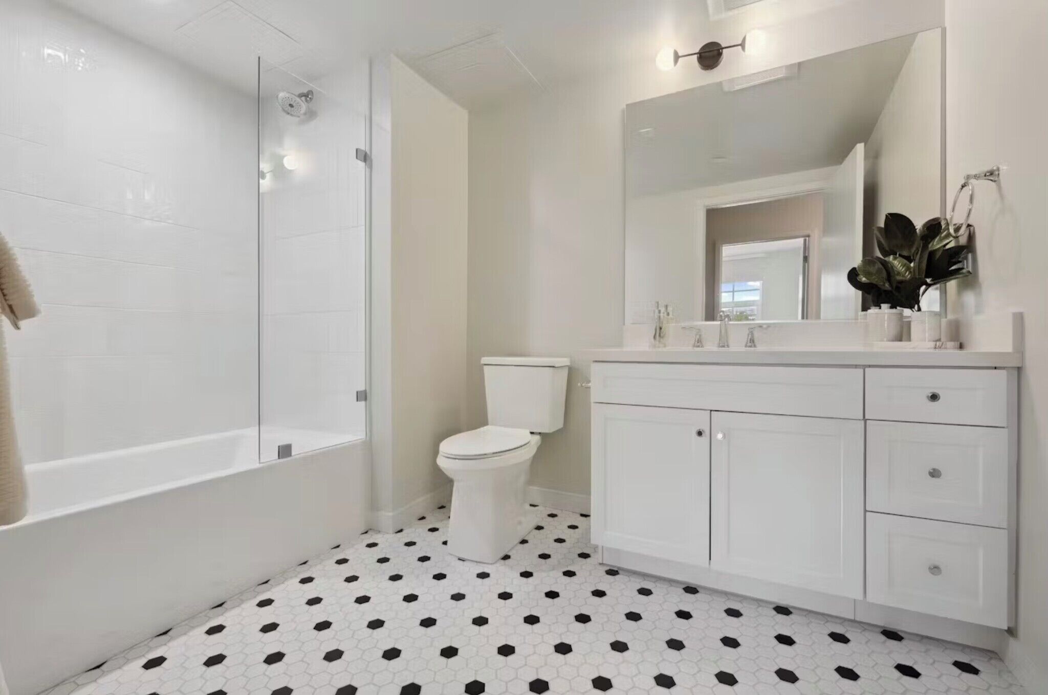 Un bagno moderno con cabina doccia in vetro, un water e un mobile lavabo bianco con cassetti.