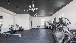Una palestra moderna con diverse attrezzature per l'allenamento, tra cui cyclette, ellittica e pesi liberi.