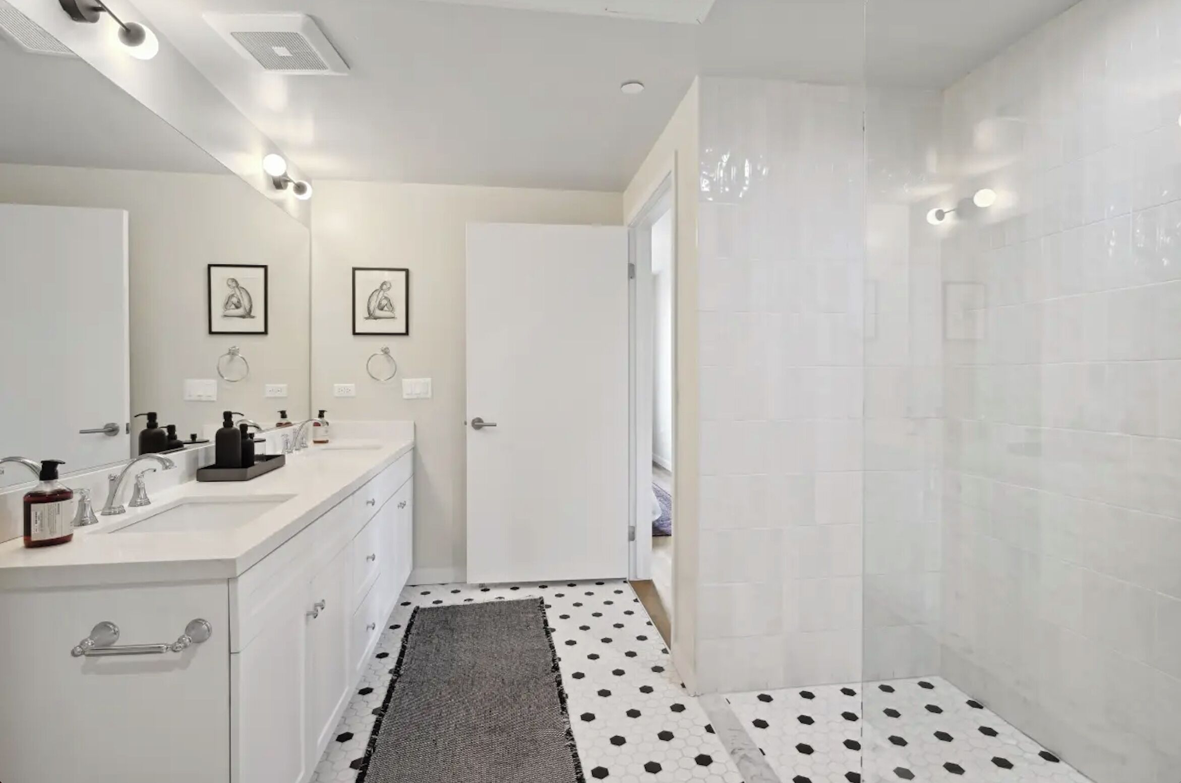 Un bagno moderno con un mobile lavabo doppio, zona doccia e pavimento a pois.
