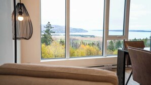A room with a large window, a bed, a table, and a chair. - 205 - Modern Suite - Pool and River View (Baie-Saint-Paul)
